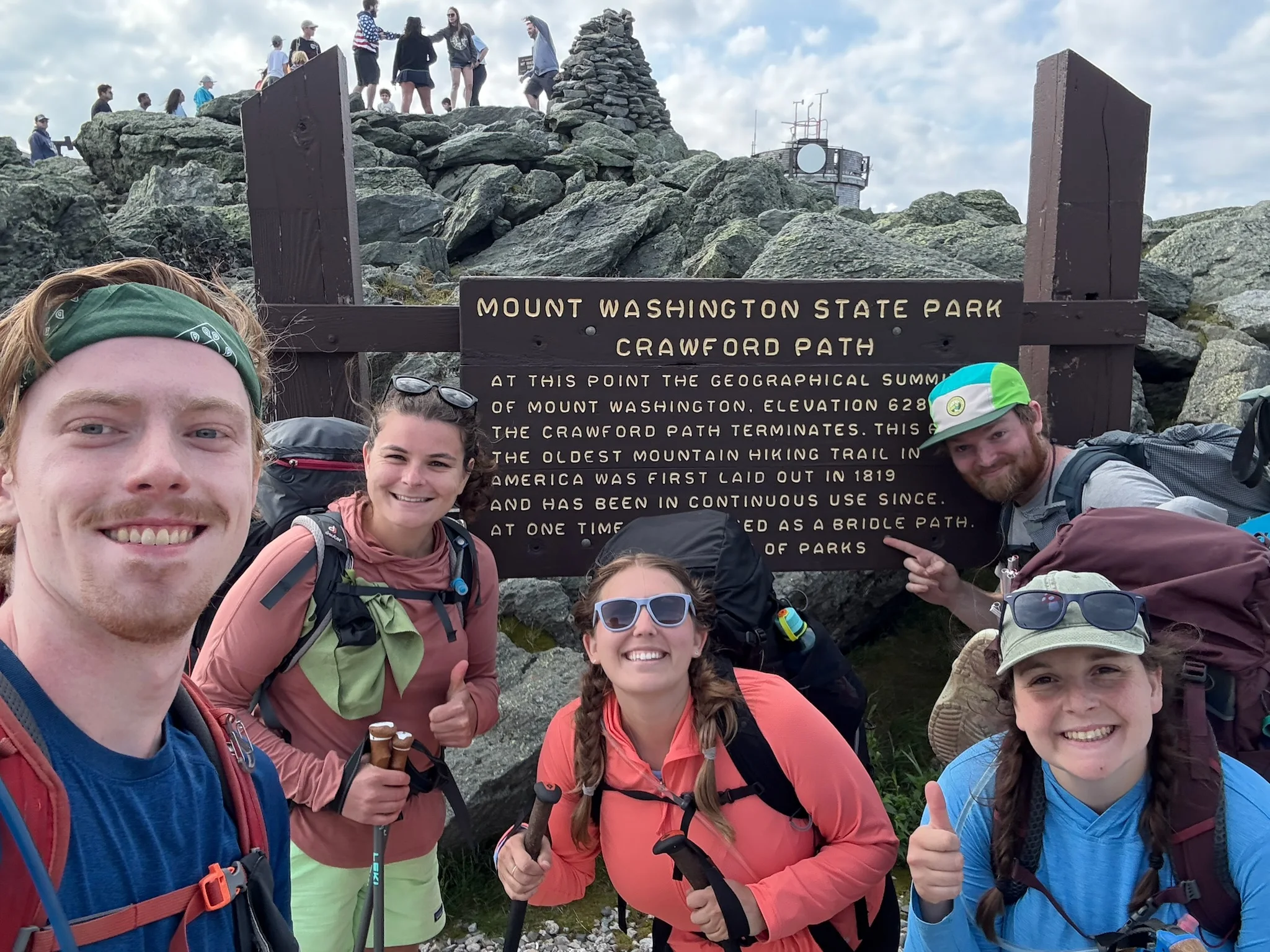 A group of hikers beside the Mount Washington summit sign.