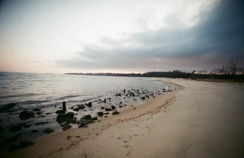 A curved shoreline with rocks beneath clouds.