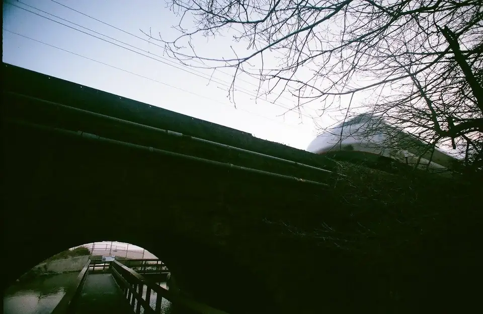 A dark brick arch beneath a bridge.