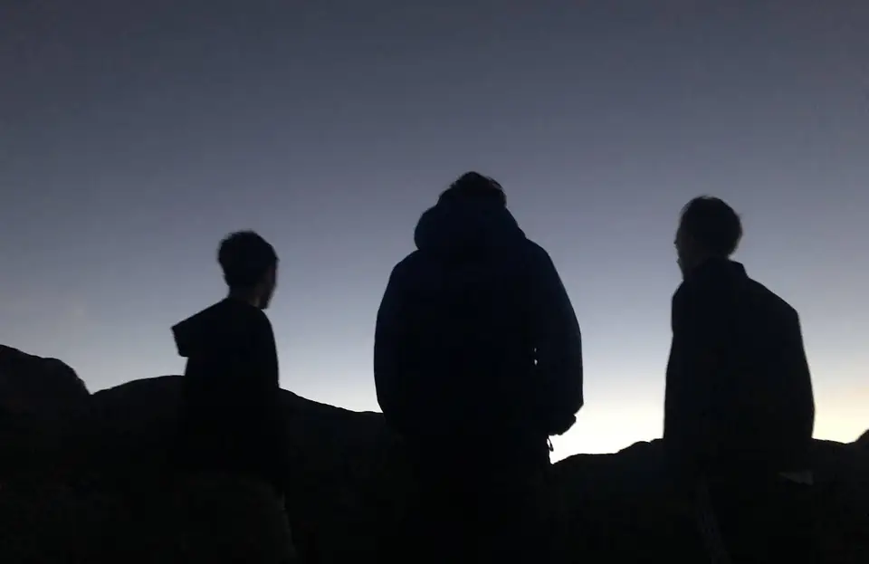Three people silhouetted against the evening sky.