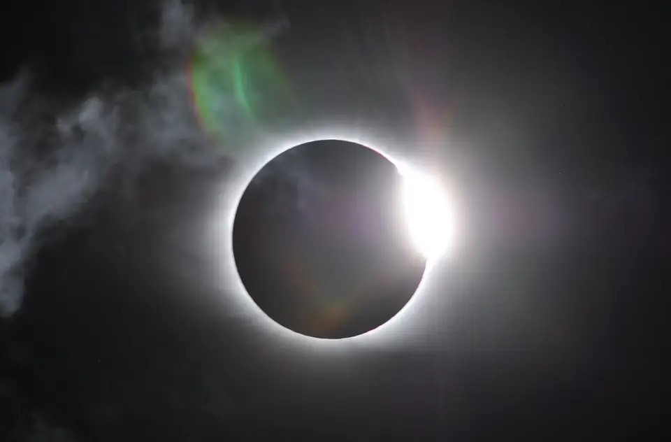The sun’s corona emerging beside a dark eclipsed disk.