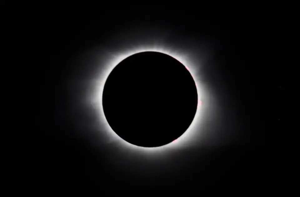 A dark eclipsed sun surrounded by a bright corona.