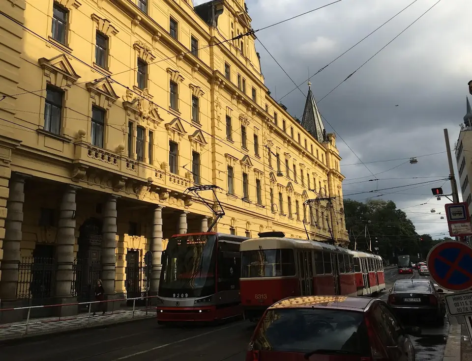 A tram beside a large yellow stone building.