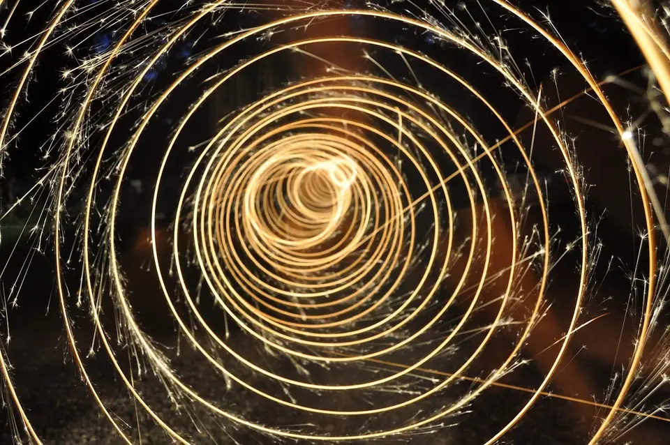 Concentric trails of golden sparks against darkness.