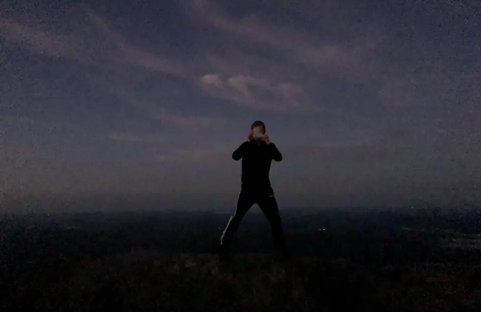 A person standing beneath a dark evening sky.